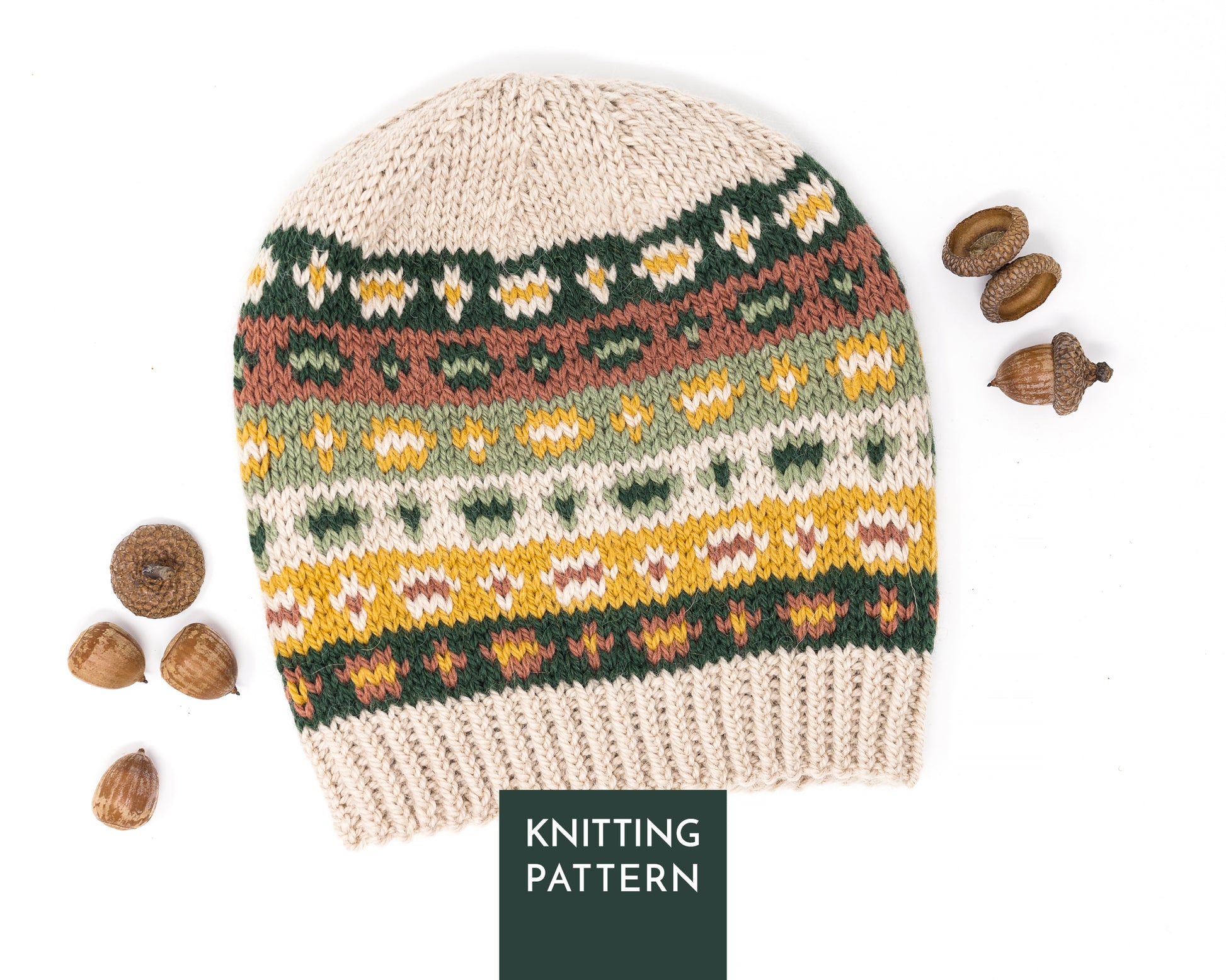 Hand-knitted Fair Isle pattern hat on a white background accompanied with acorns