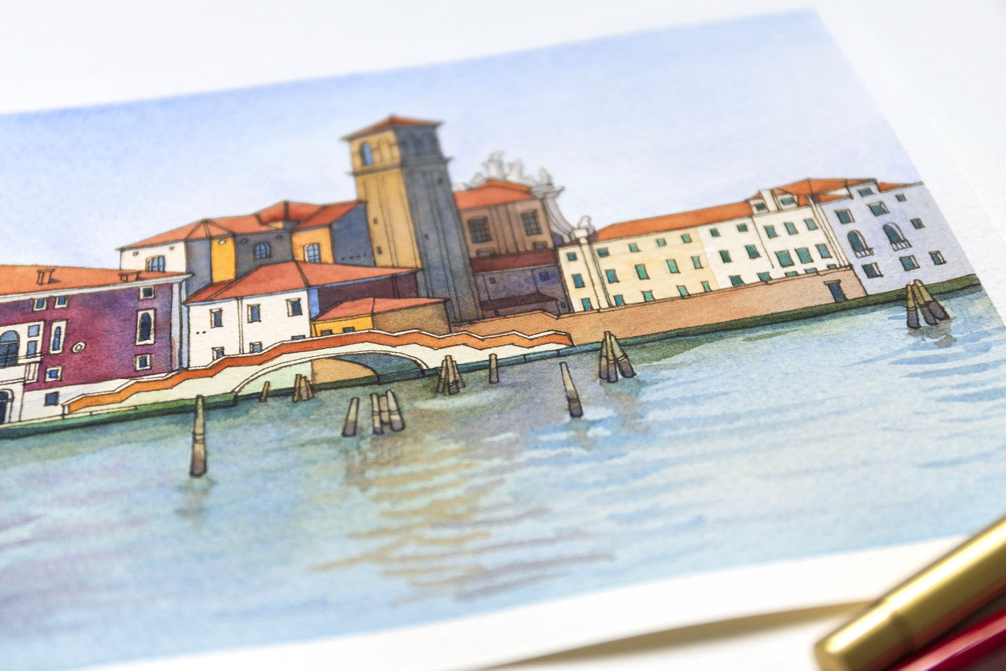 Close-up of an original watercolor and ink artwork of Venetian Fondamenta Nova with buildings and a bridge over water.