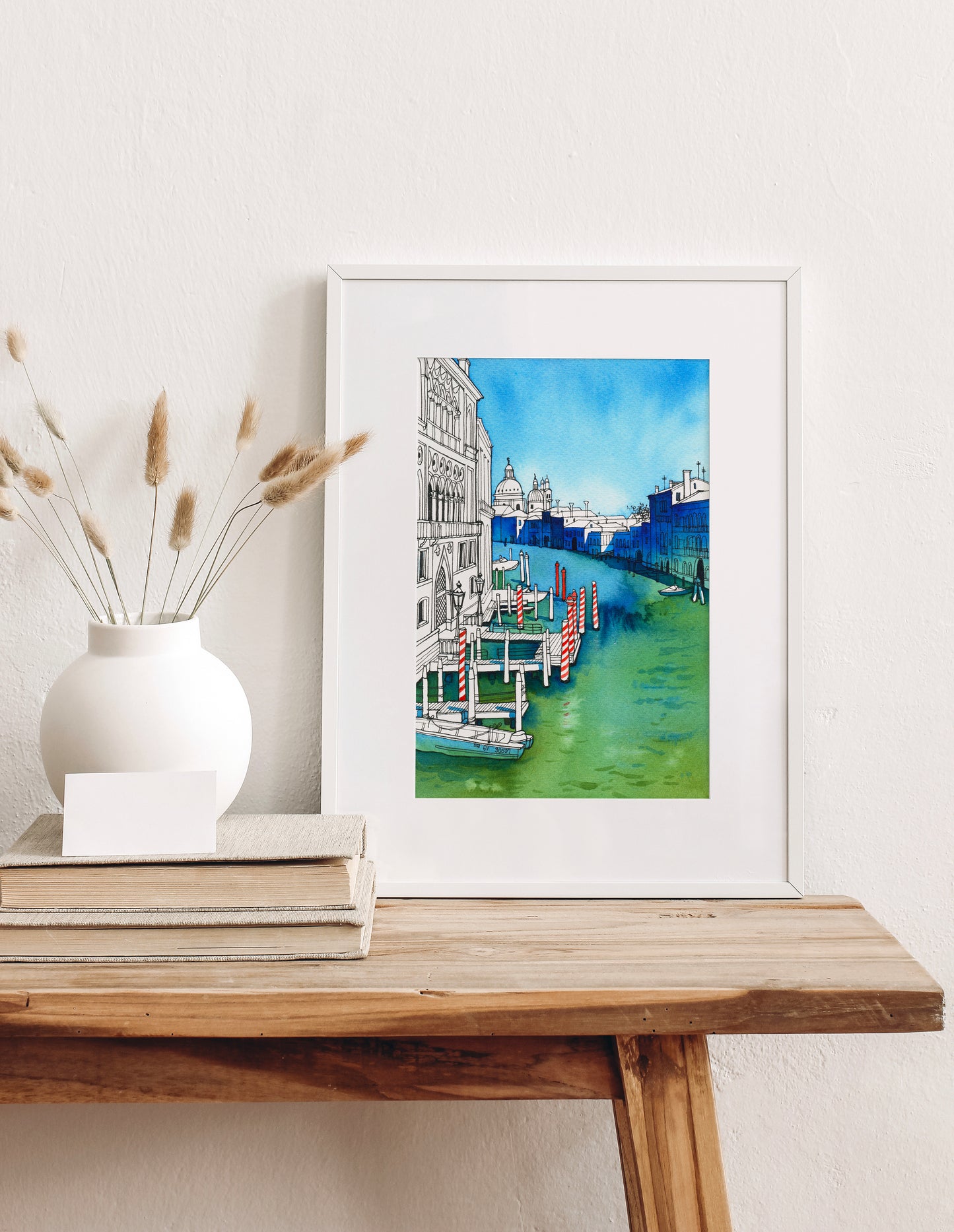 Framed watercolor artwork of Venetian Grand canal viewed from the Accademia Bridge on a wooden table with decorative elements.