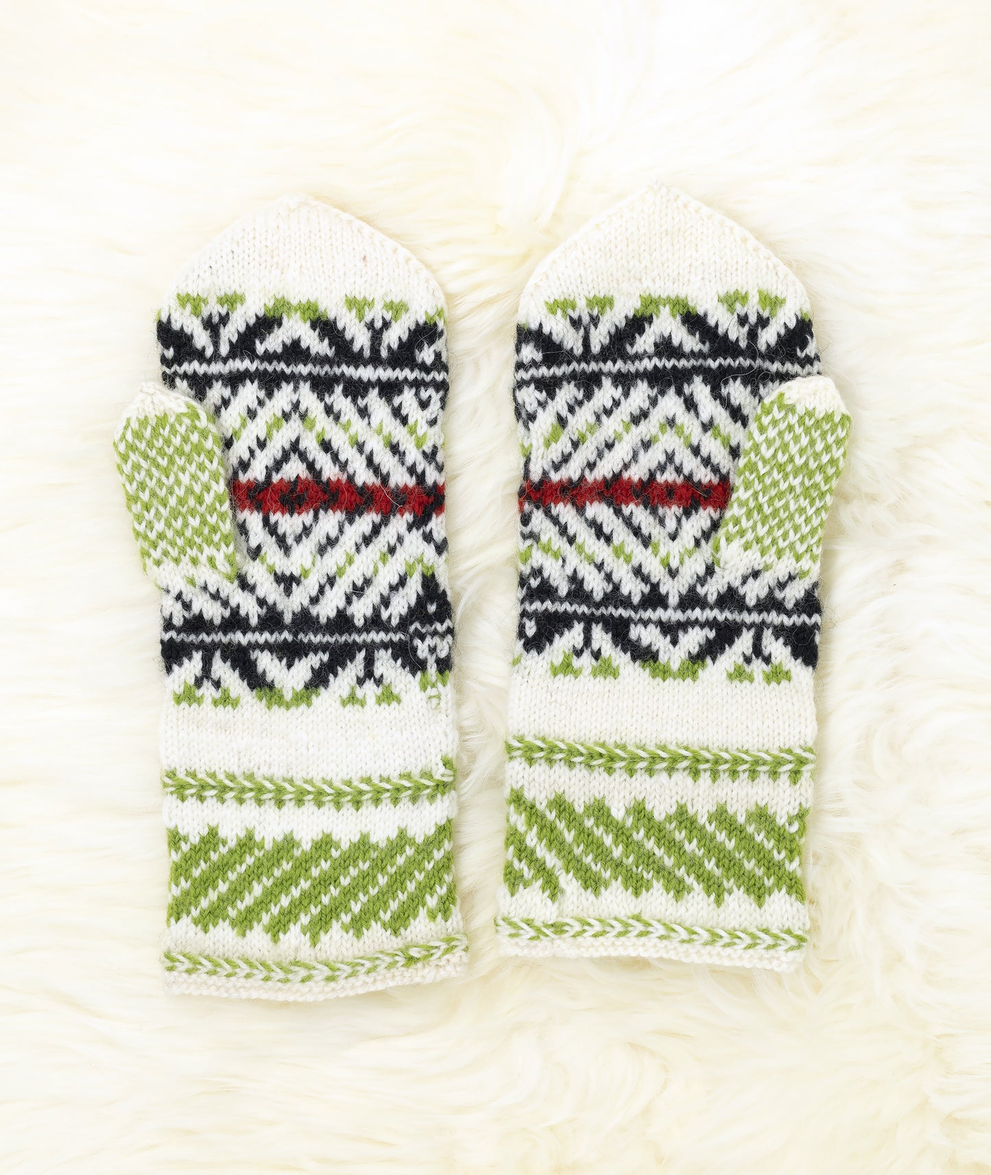 Palm and thumb of white, black, green and red hand-knitted mittens in traditonal Estonian pattern on a white background