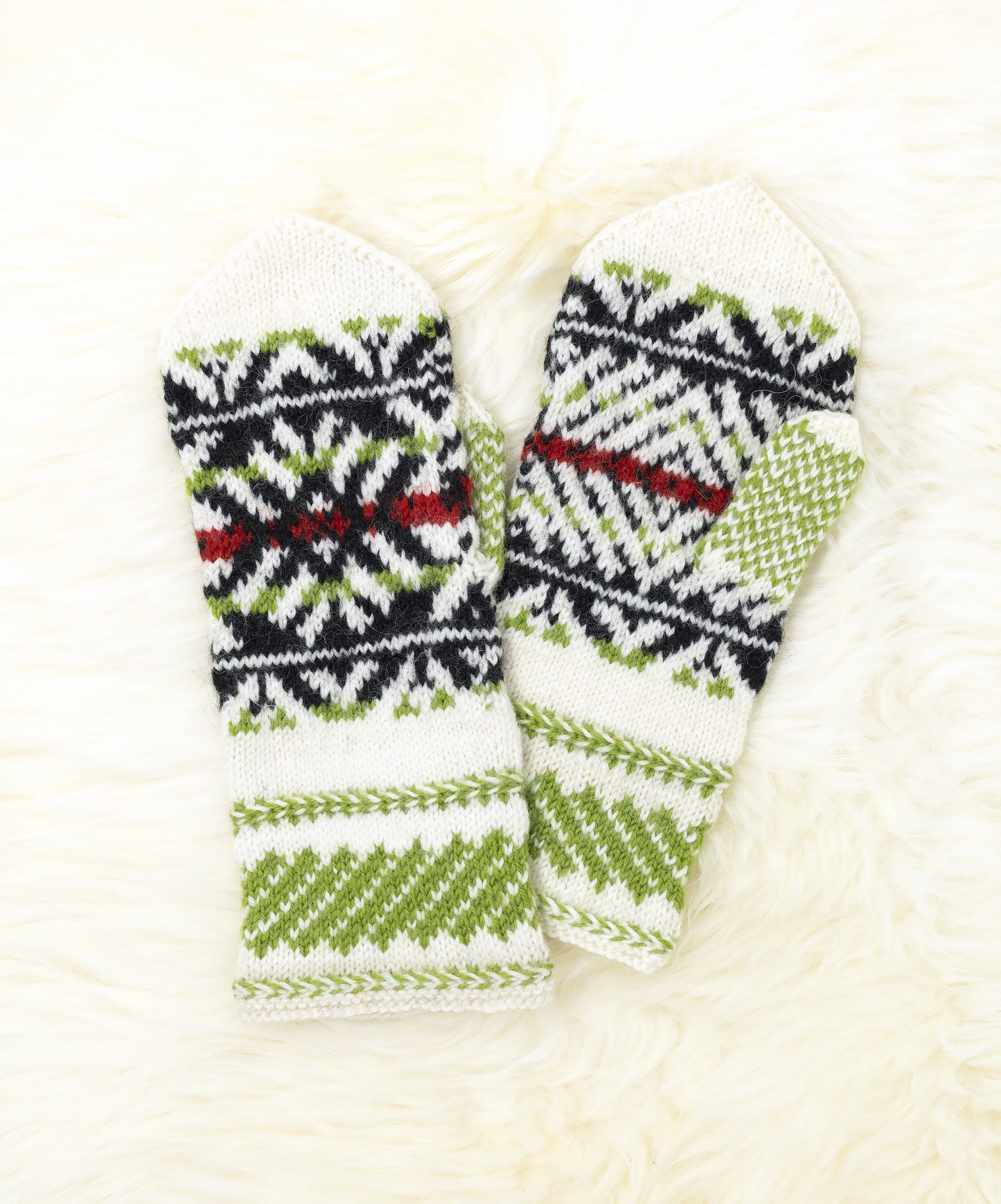 Pair of white, black, green and red hand-knitted mittens in traditonal Estonian pattern on a white background